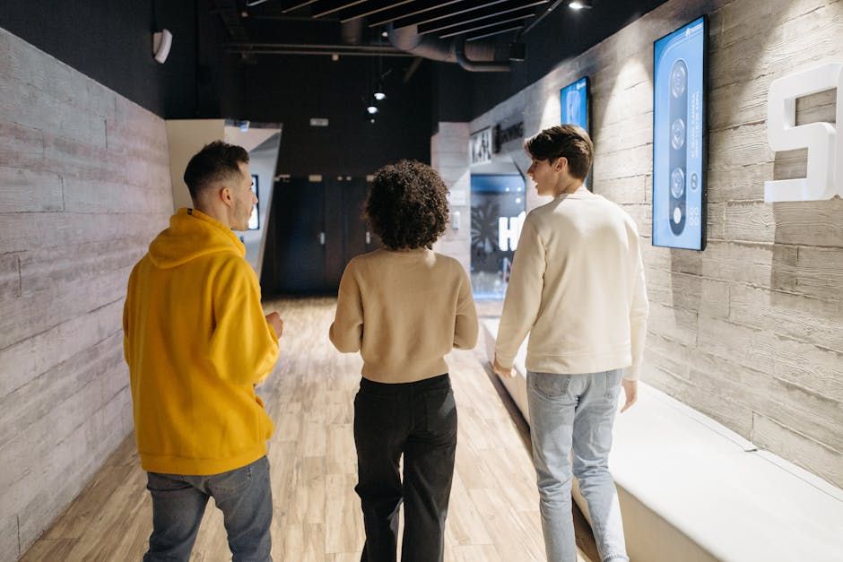 Three friends walking together inside a trendy hallway with digital displays.